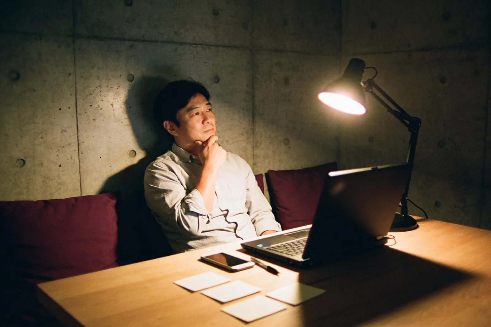 深夜，講師坐在檯燈下，一手托著下巴在想事情，面前的筆電開著，桌上擺著幾張空白卡片。